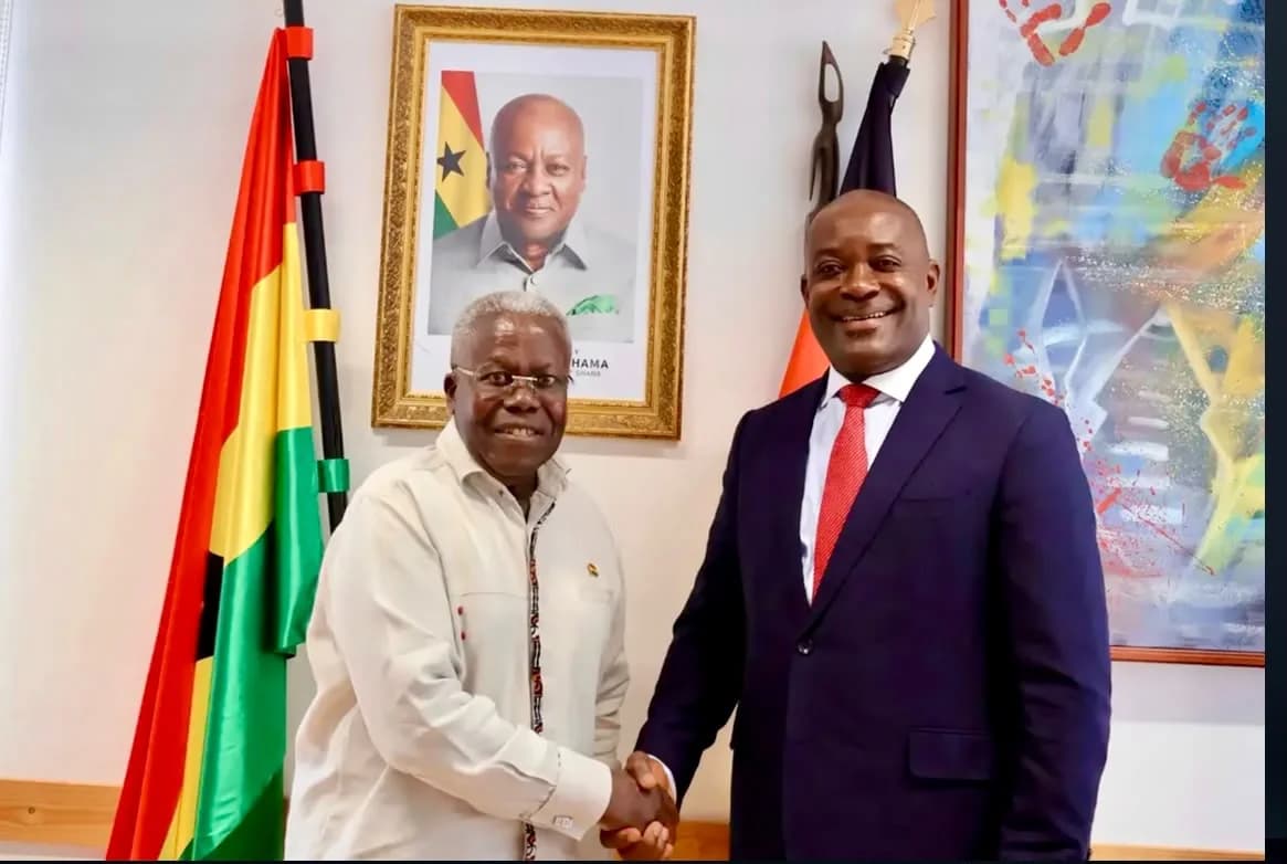 Two participants shaking hands beside Ghanaian flags.