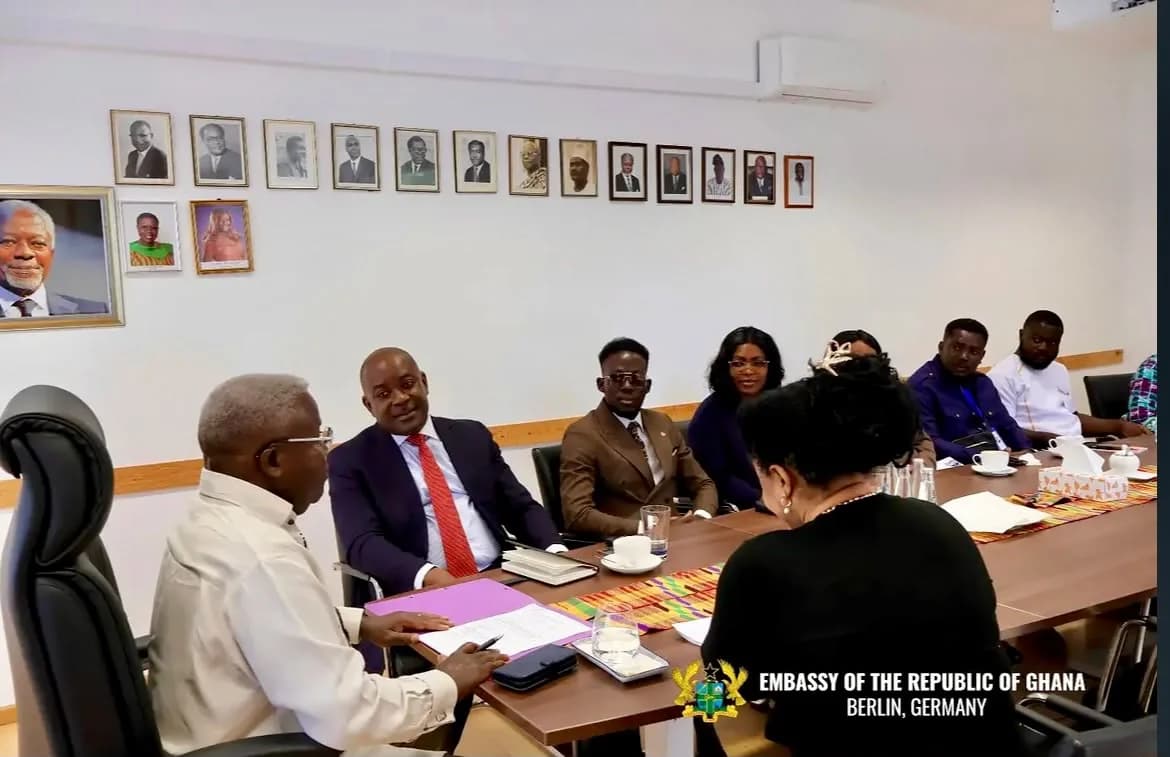 Delegation members seated around a conference table with papers and refreshments.
