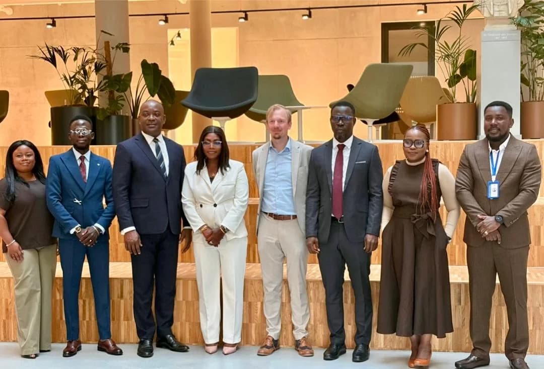 Eight delegation participants posing for a group photograph in an indoor seating area.